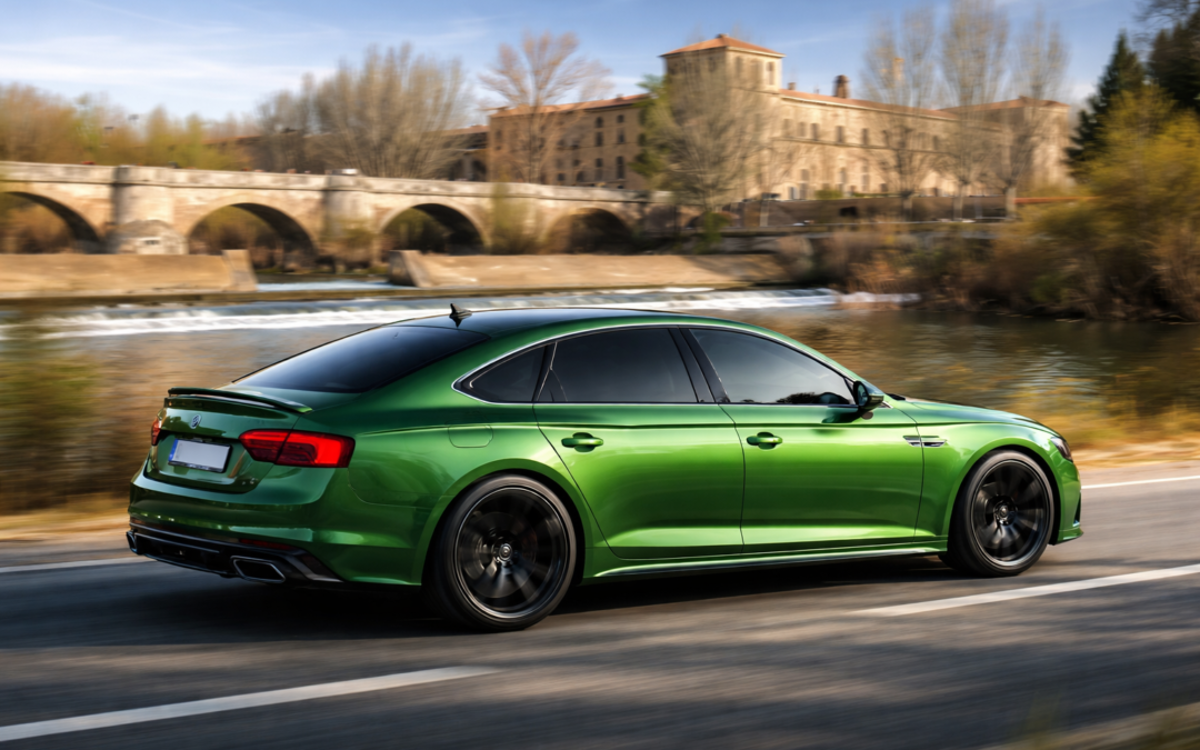 Audi verde eléctrico en movimiento con lunas tintadas circulando junto a un río, imagen que representa las ventajas del tintado de lunas para mejorar la estética, la privacidad y el confort del vehículo.