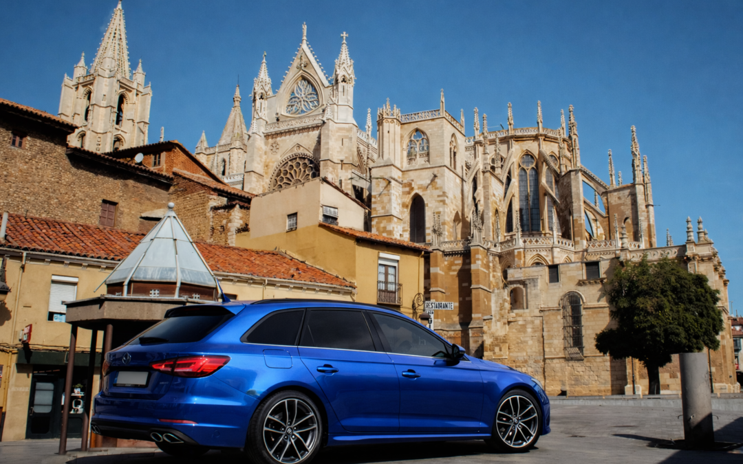 Coche familiar azul con lunas tintadas aparcado frente a la Catedral de León, destacando el tintado profesional en un entorno urbano histórico.
