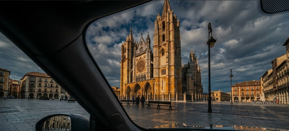 Vista horizontal de la Catedral de León capturada desde el interior de un coche a través de una luna tintada.