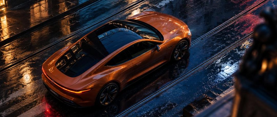 Coupé deportivo naranja con lunas tintadas circulando por una calle urbana mojada de noche.